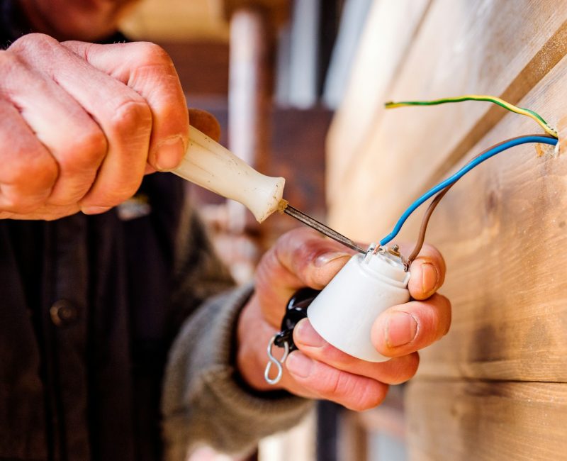 Hands of unrecognizable electrician working with screwdriver